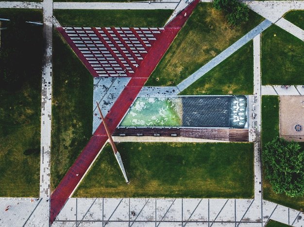 An aerial view of a modern, eco-friendly office building with solar panels and green roofs, set against a backdrop of a lush urban park.
