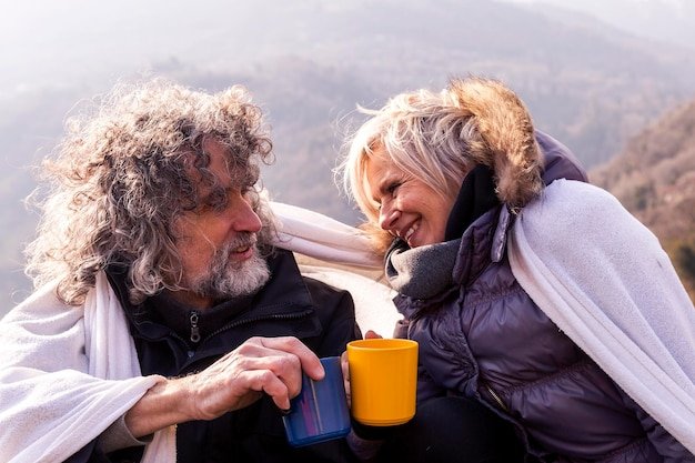 A younger couple in their late 50s, hiking in the mountains and smiling, symbolizing an active early retirement lifestyle.