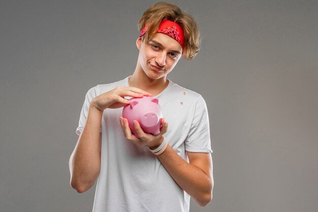 A person putting money into a piggy bank with a determined expression, symbolizing disciplined saving habits for building an emergency fund.