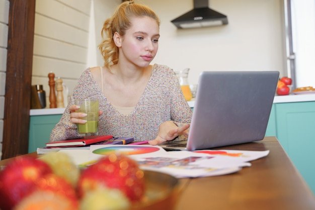 A student engrossed in studying a colorful infographic about money management on her laptop. The image captures her focus and engagement, emphasizing the potential of digital tools in financial literacy education.