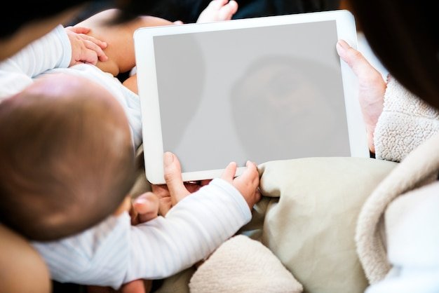 A new parent reviewing a budget on a tablet while holding a baby, illustrating ongoing financial adjustments.