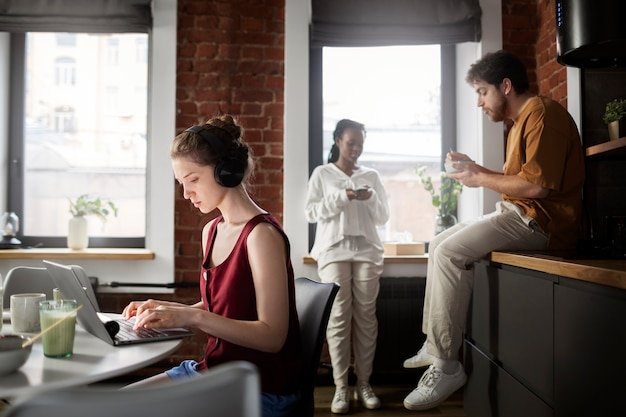 A modern co-living space with shared kitchen and living areas, showing young professionals interacting and using the facilities. The image highlights the communal aspects and cost-saving benefits of co-living.