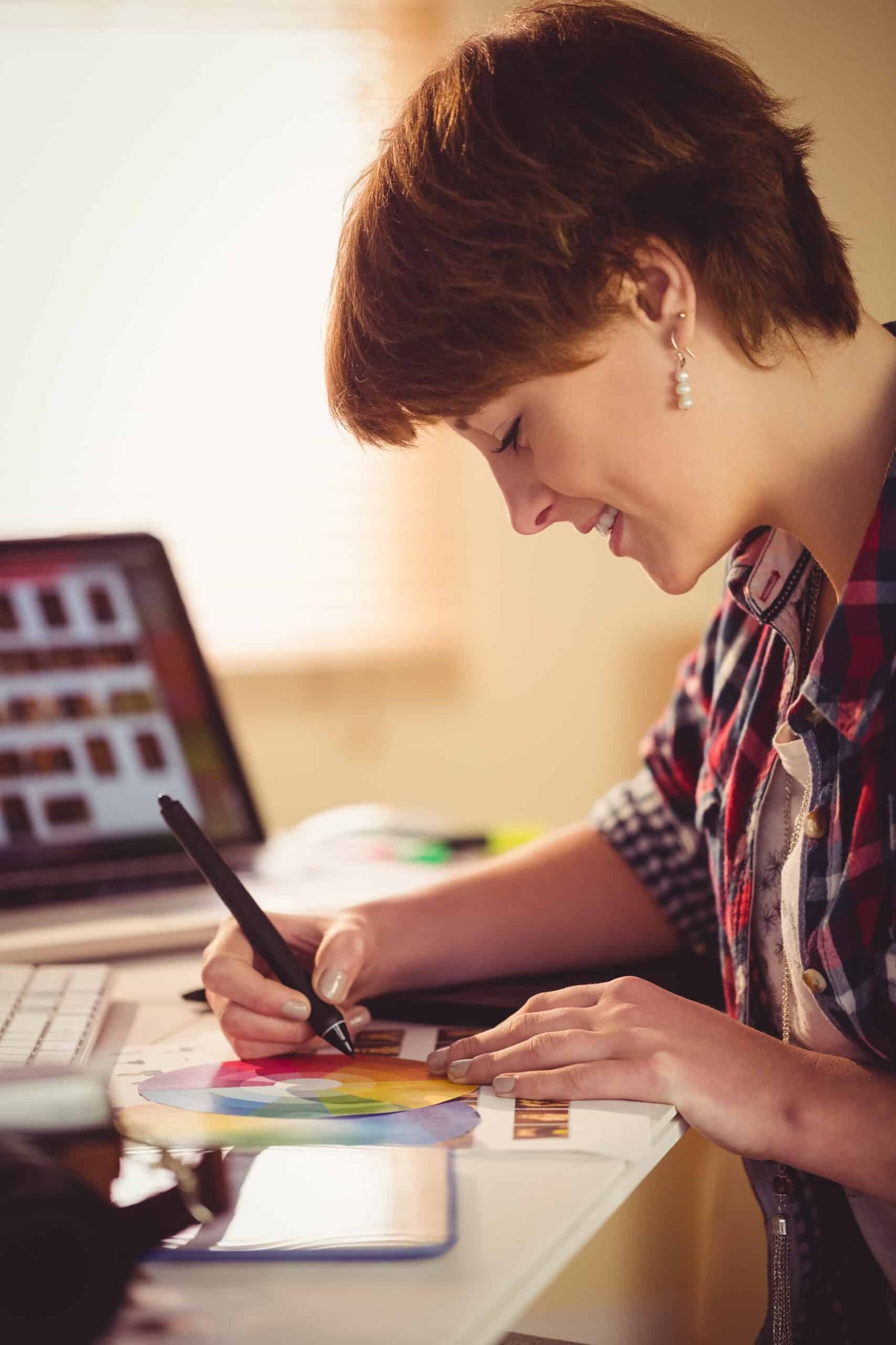 A person designing a digital product on a tablet in a bright, modern workspace, with icons representing e-books, online courses, and templates floating around.
