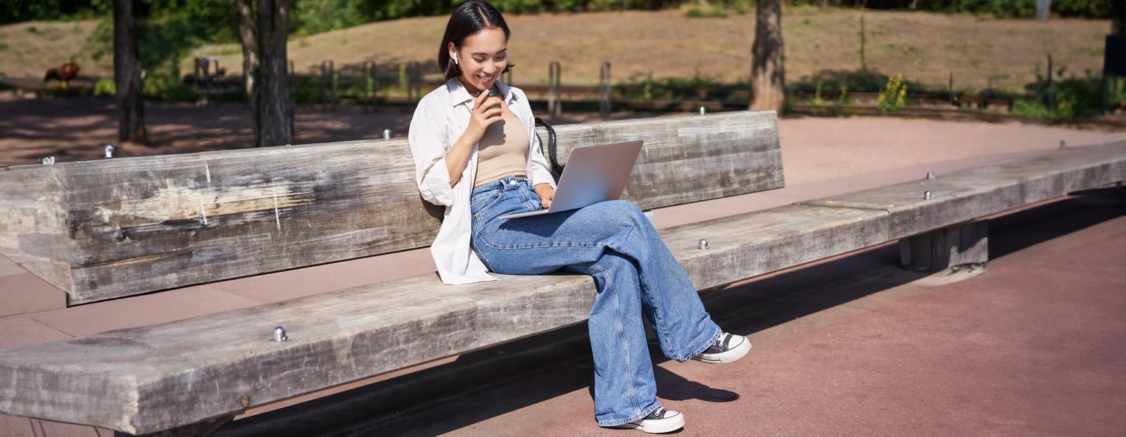 A millennial sitting at a laptop, smiling and looking relaxed, with a beach scene visible through the window, symbolizing a comfortable retirement.